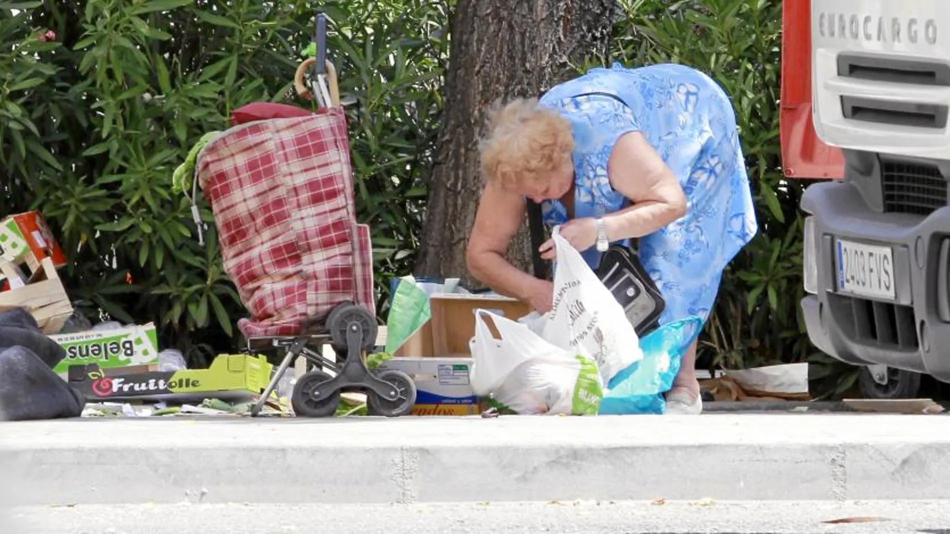 Ropa, alimentos y todo lo que quede por el suelo lo aprovechan las personas que aguardan al final de los mercadillos (en la imagen el de Villa de Vallecas) para poder llevarse algo a casa
