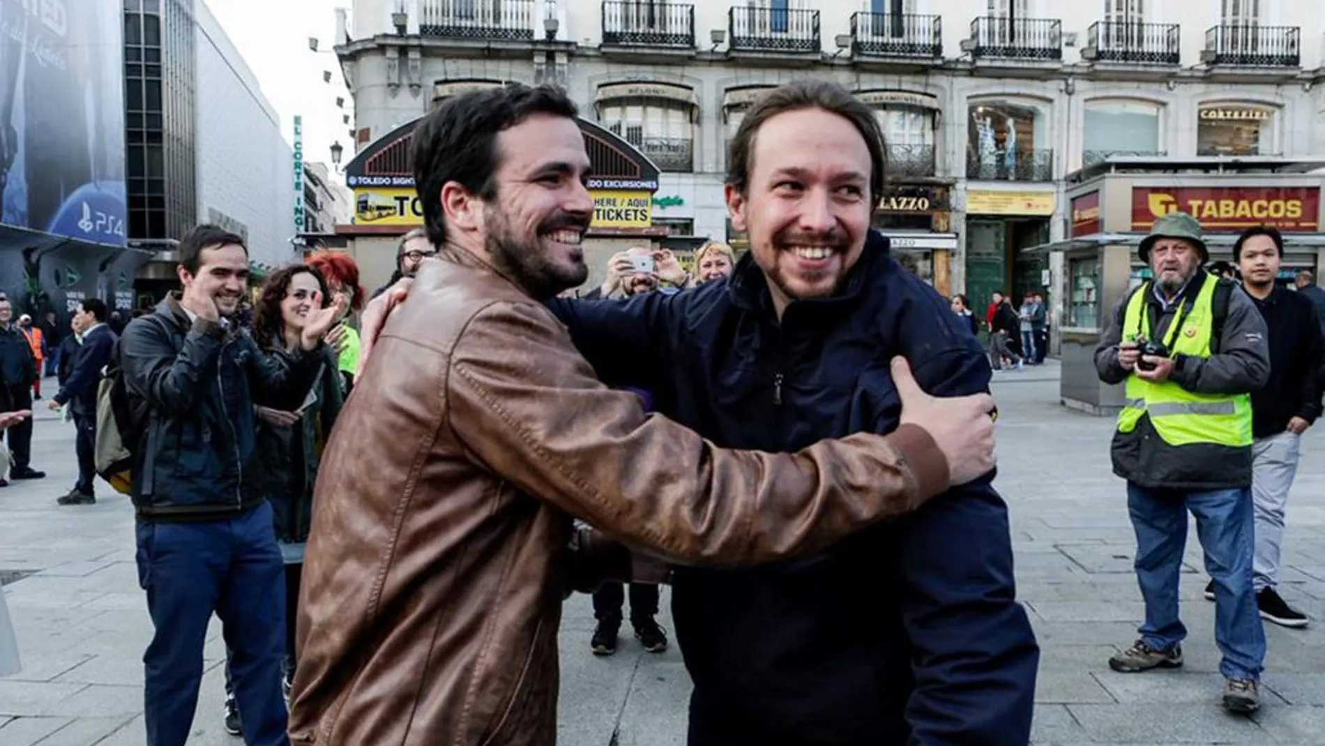 Los líderes de Podemos, Pablo Iglesias (d), y de IU, Alberto Garzón (i), dándose un abrazo en la Puerta del Sol