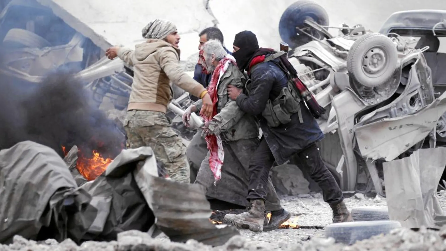 Combatientes rebeldes ayudan a un hombre herido por la explosión de un coche bomba, ayer en Jub al Barazi, al norte de Al Bab
