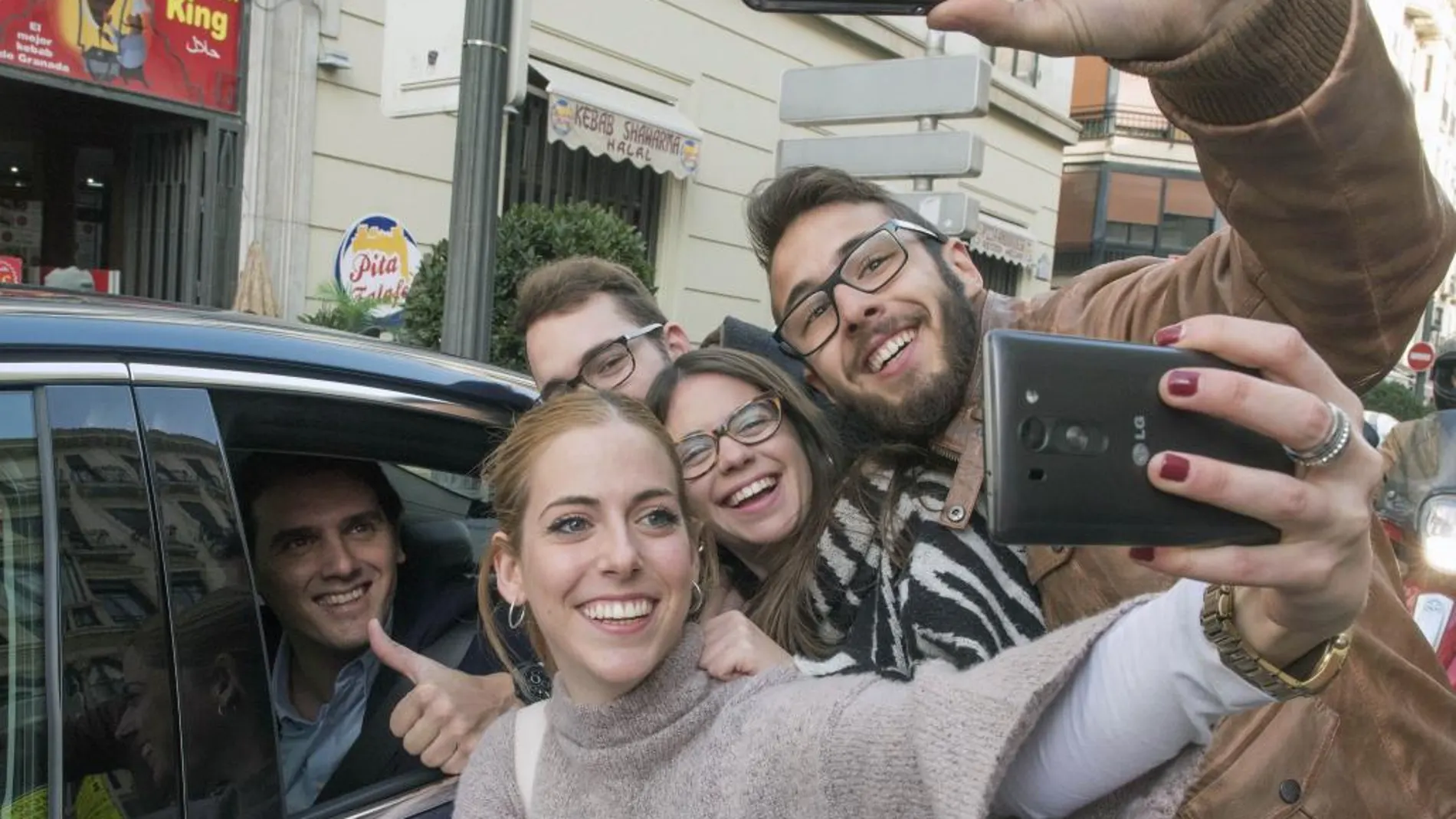 El presidente de Ciudadanos y candidato a la presidencia del Gobierno, Albert Rivera, dentro del coche se deja hacer un selfie con un grupo de jóvenes tras participar hoy en un acto de campaña en la Plaza Nueva de Granada