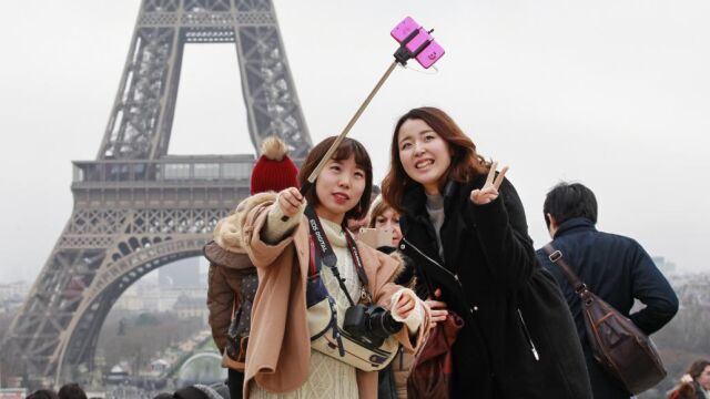 Dos turistas se hacen un selfie frente a la torre Eiffel