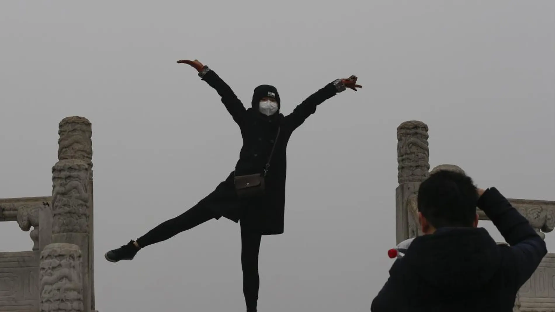 Una mujer posa para una foto mientras usa una mascarilla para protegerse contra la contaminación ambiental durante una visita al Templo del Cielo de Pekín (China), el pasado 8 de diciembre
