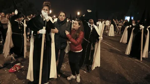 Nazarenos de La Esperanza de Triana visiblemente afetados tras sufrir una estampida durante su recorrido procesional a su paso por el puente de Triana