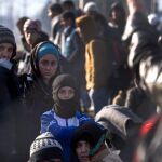 Un grupo de afganos aguardan tras la valla tras no obtener permiso para cruzar a territorio macedonio procedentes de Grecia.