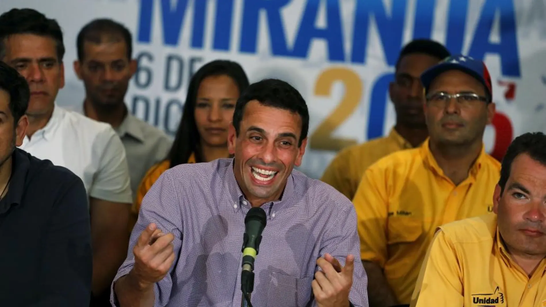 El líder opositor venezolano, excandidato presidencial y gobernador del estado Miranda, Henrique Capriles (d), sonríe al ofrecer una conferencia de prensa, acompañado de varios de los 99 diputados electos