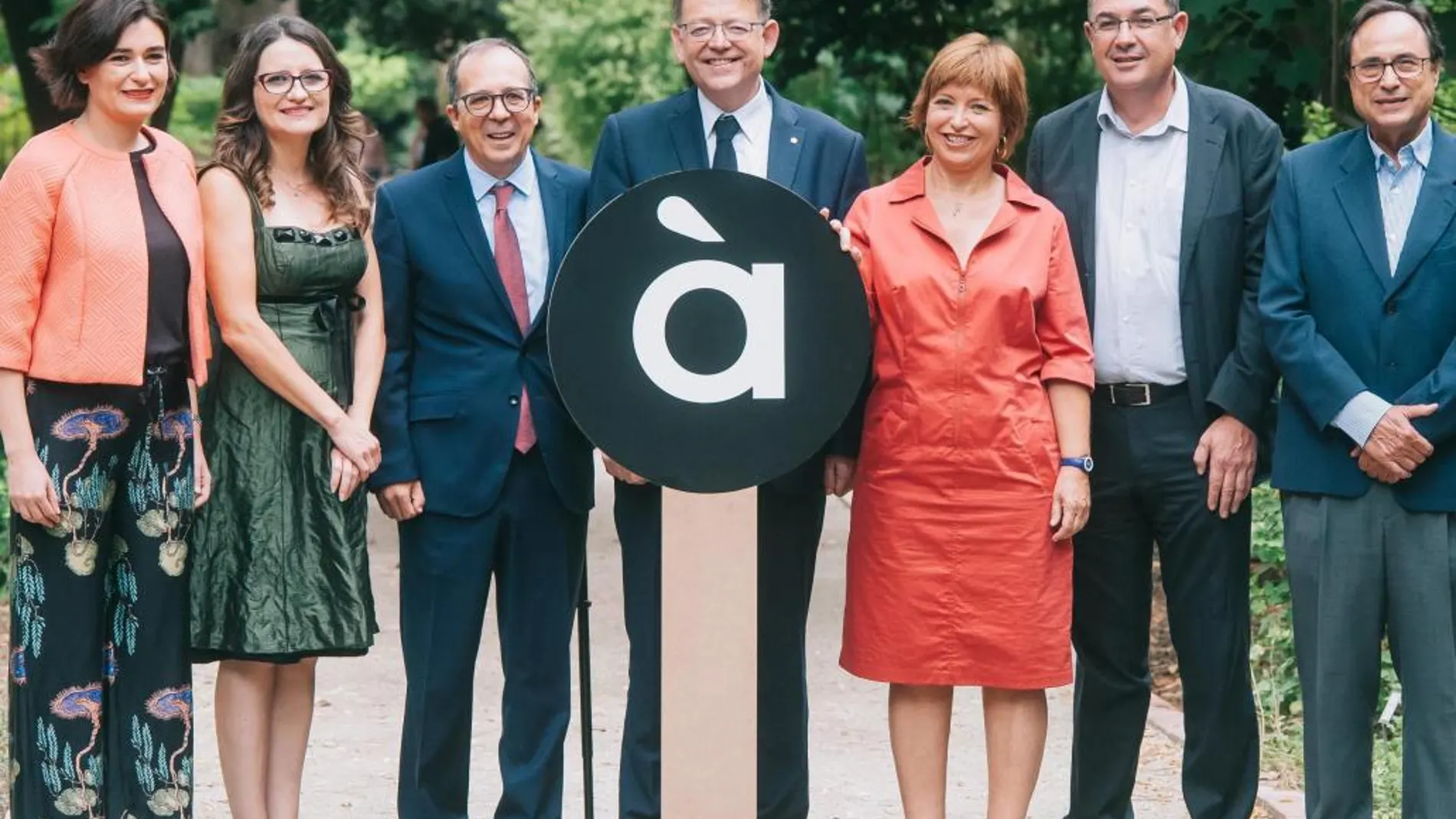 Montón, Oltra, Soriano, Puig, Marco, Morera y Soler, posan delante del logo de À punt en el Jardín Botánico, durante la presentación a la que asistió medio Consell