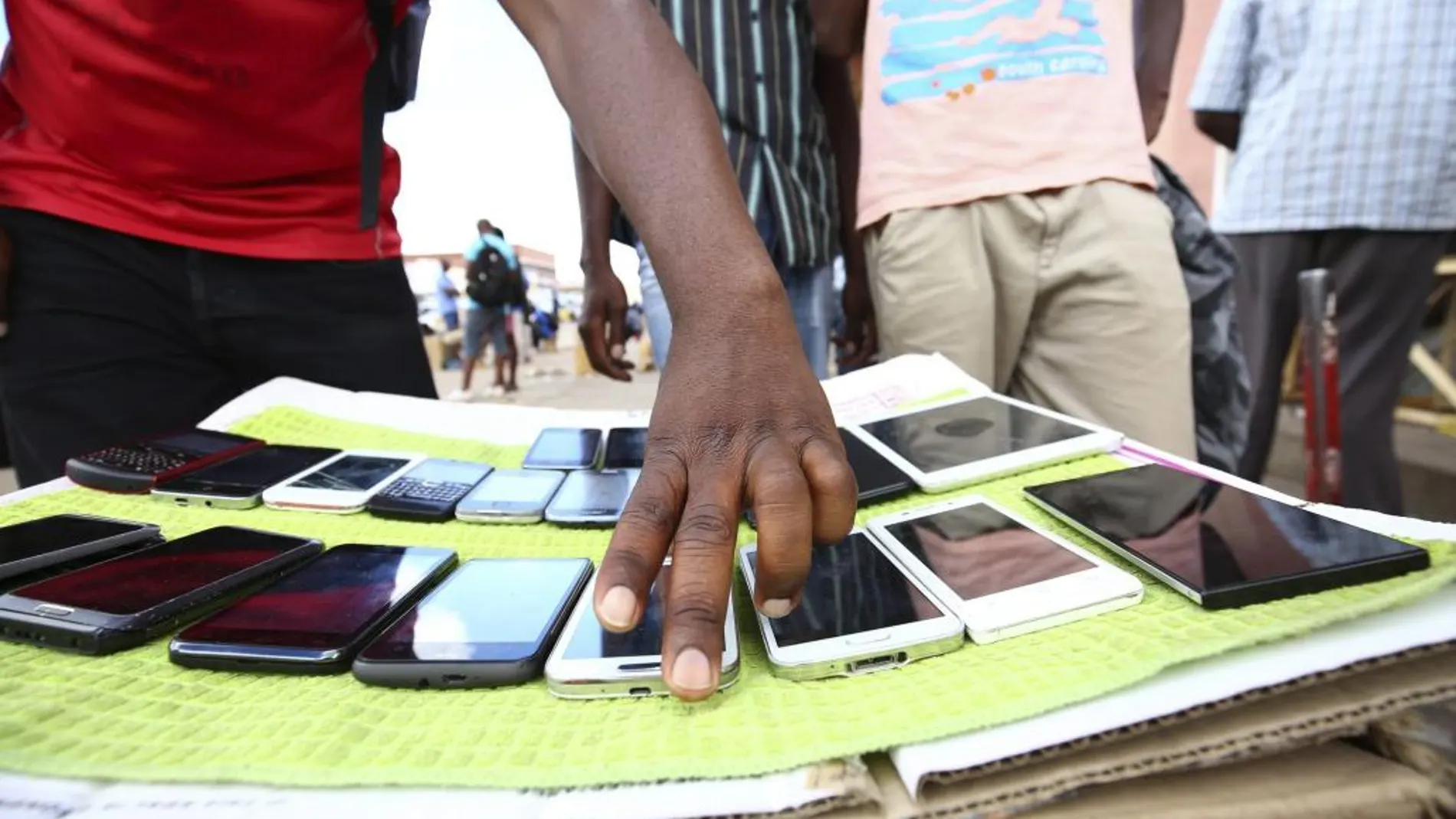 Un zimbabuense vende teléfonos móviles en los alrededores de un centro comercial del centro de Harare (Zimbabue).