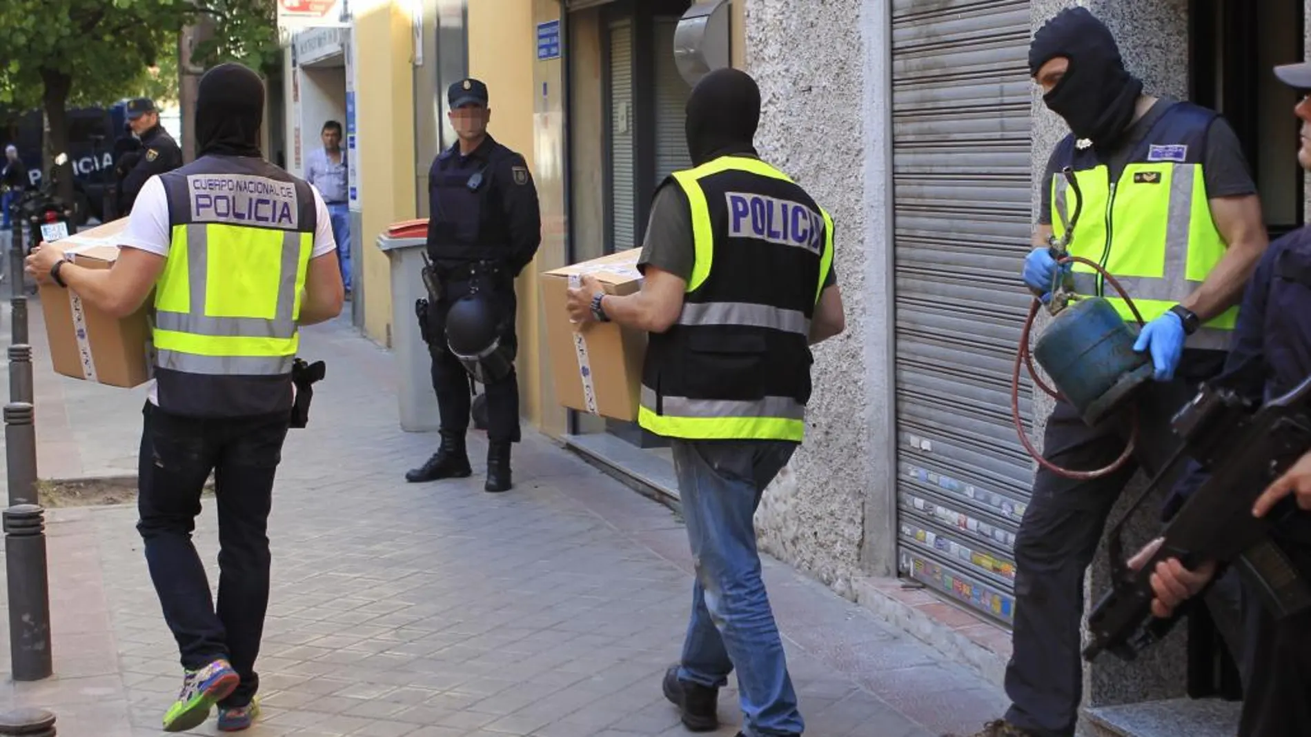 Efectivos de la polícia trasladan material requisado en el domicilio de uno de los detenidos
