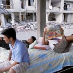 Supervivientes pasan el tiempo entre las ruinas de Manta leyendo un periódico local