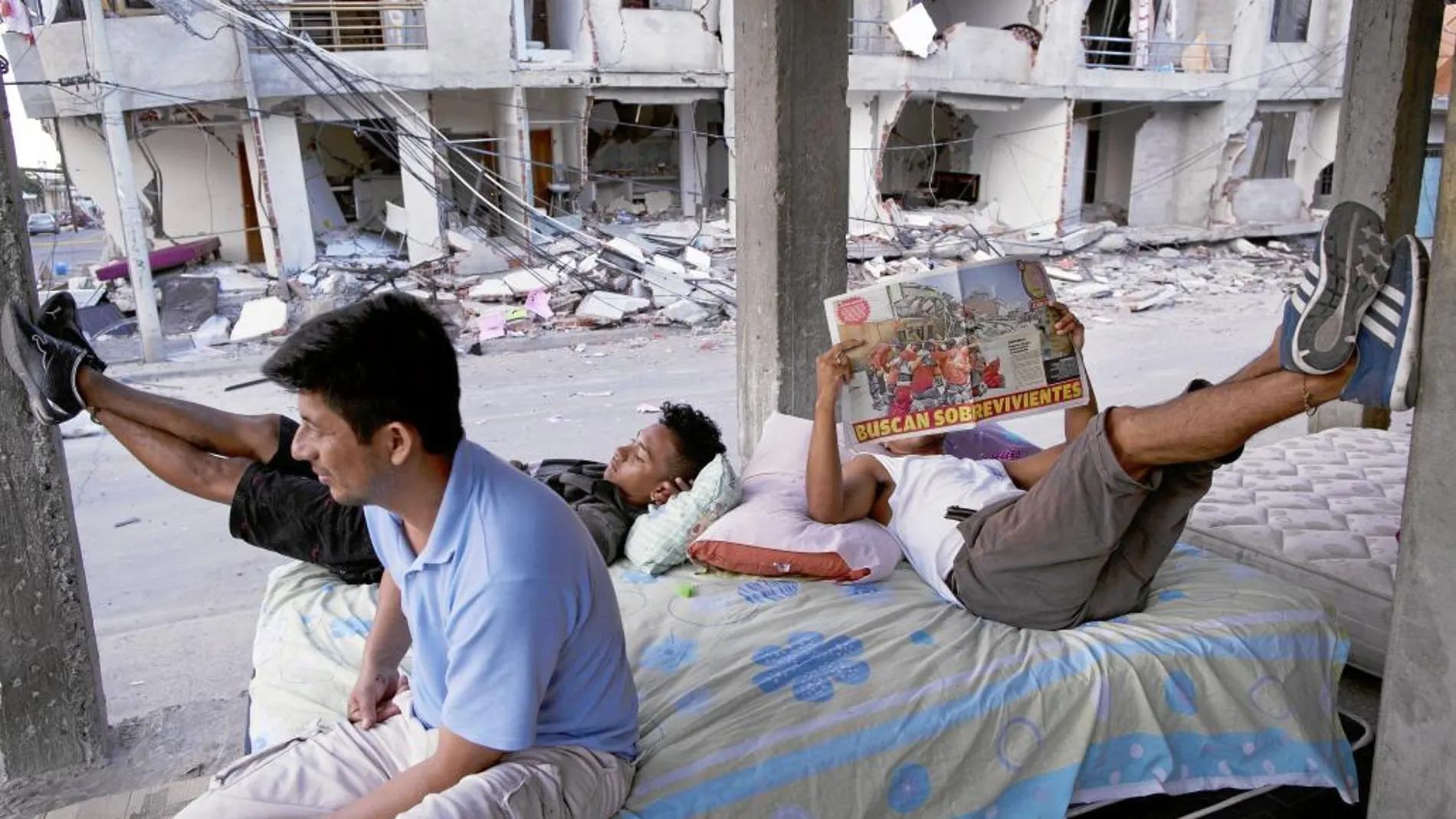 Supervivientes pasan el tiempo entre las ruinas de Manta leyendo un periódico local