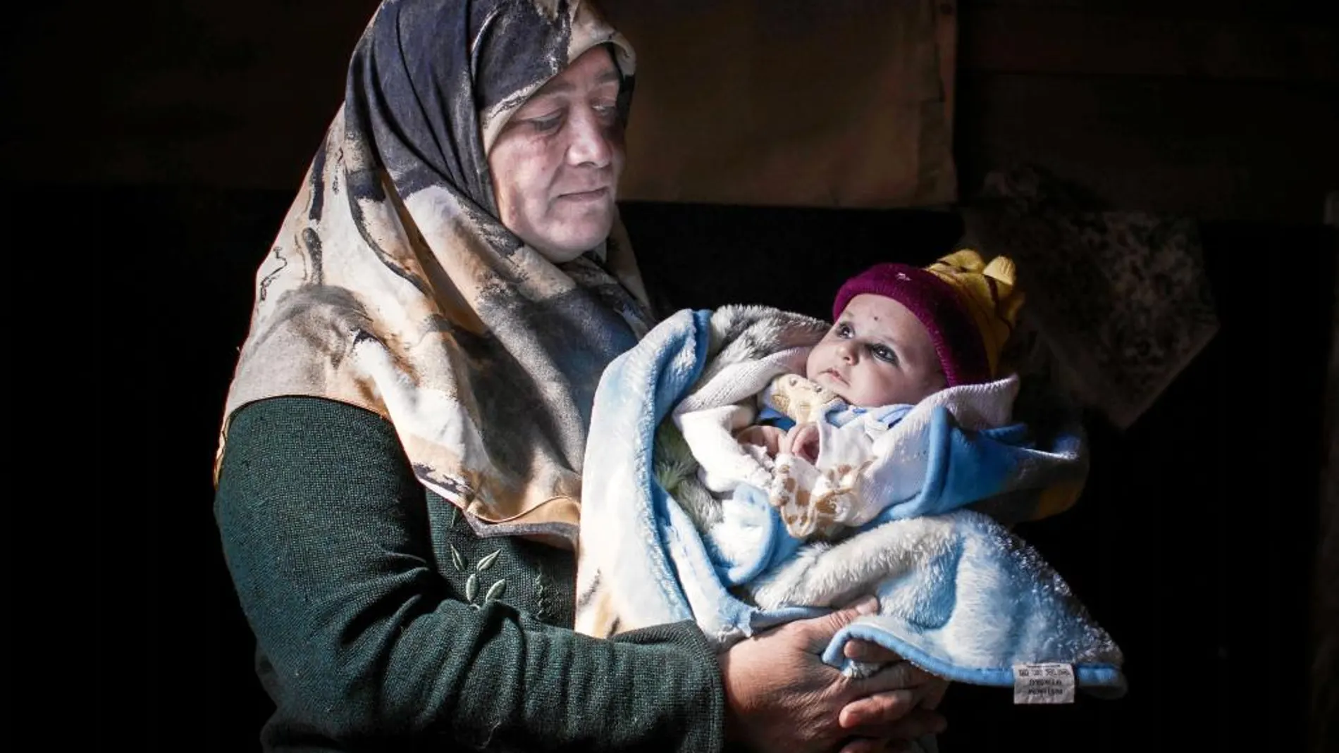 Umm Azem posa con su nieto en brazos en la tienda que ocupa con su familia en el valle de La Bekaa