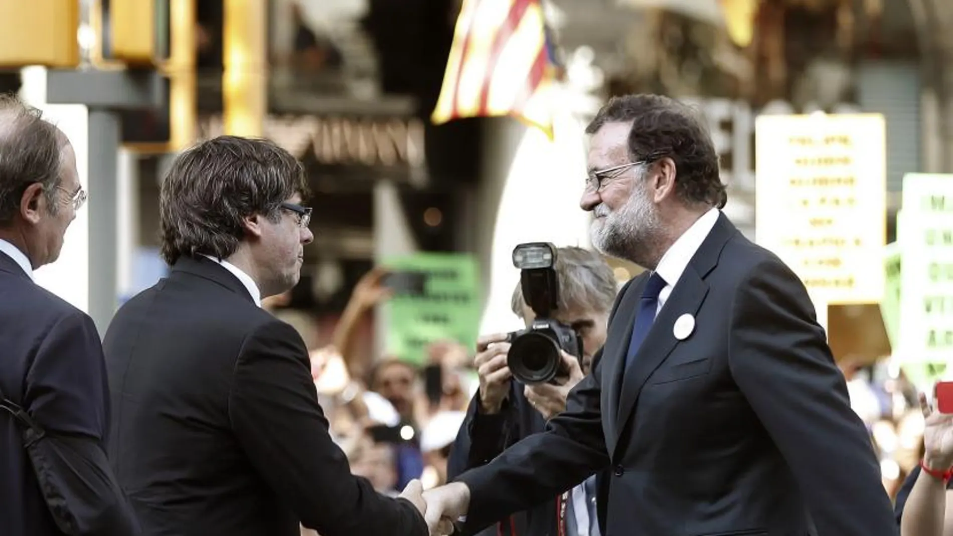 El presidente del Gobierno Mariano Rajoy (d) saluda al presidente catalán Carles Puigdemont (i) durante la manifestación de ayer en Barcelona