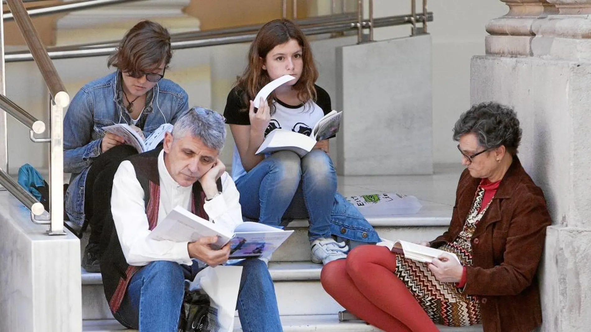 Varios lectores apostados en la Plaza Nueva de Sevilla, donde se celebra anualmente la Feria del Libro