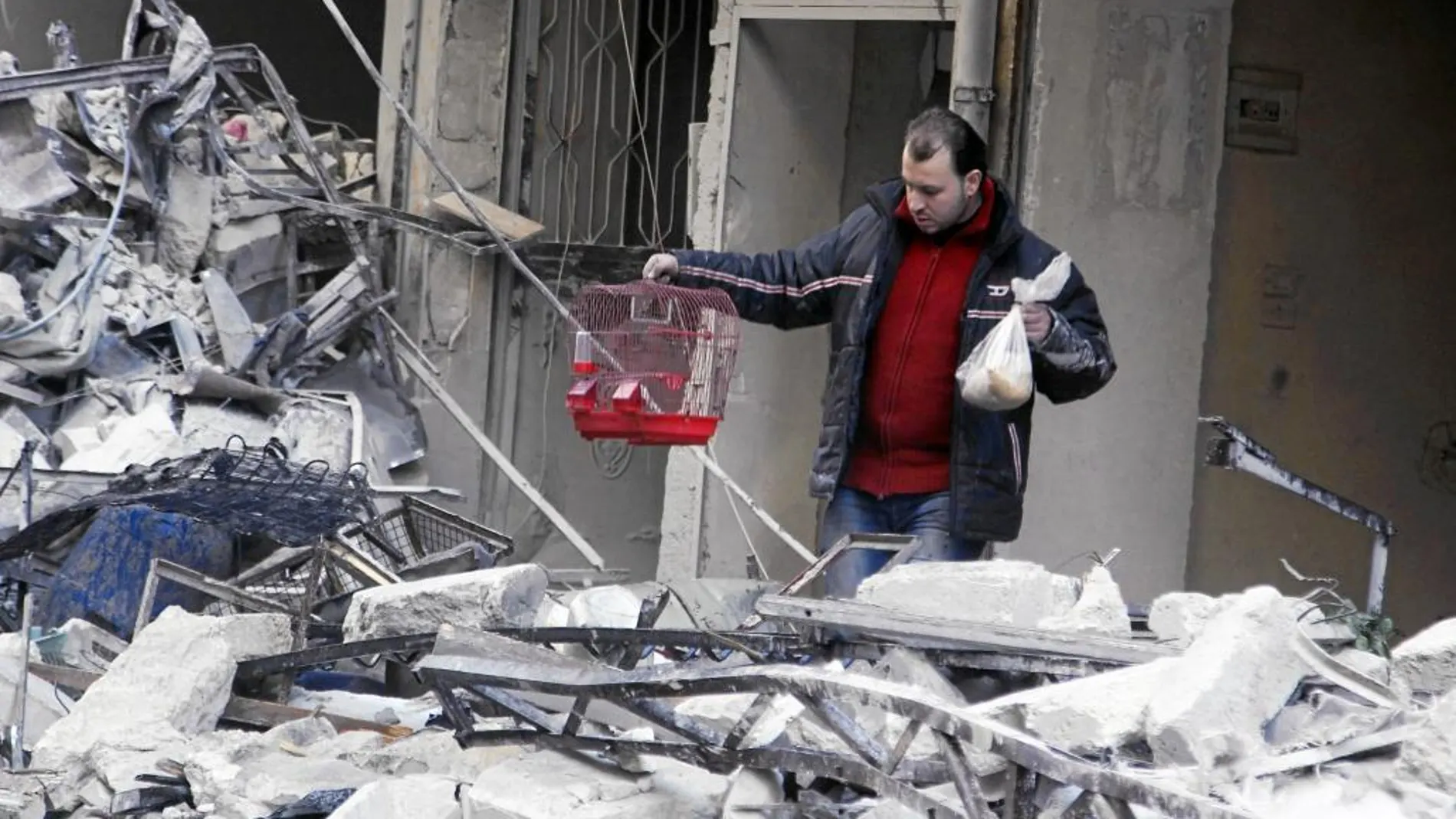 Un sirio saca una jaula tras los bombardeos de Asad en un barrio al norte de Alepo, ayer