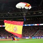 Un paracaidista con una bandera española aterriza en el terreno de juego del Wanda Metropolitano, en Madrid