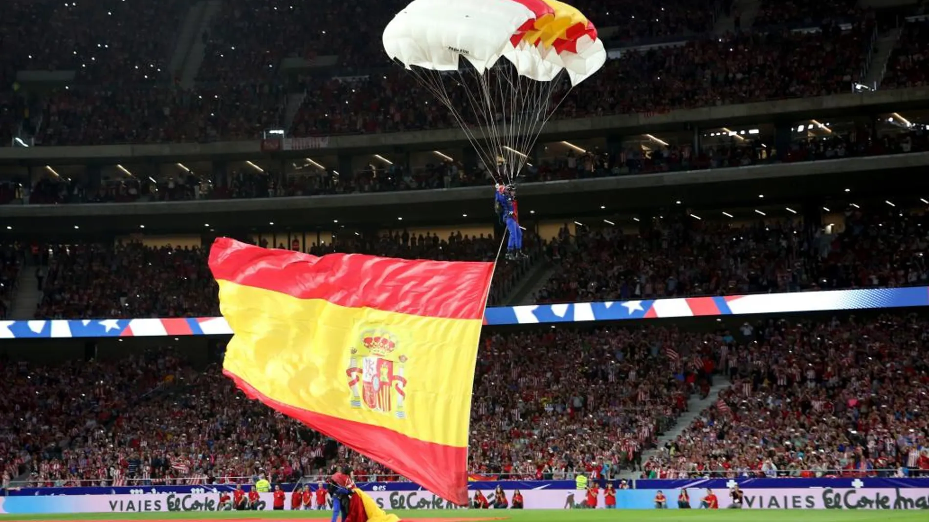 Un paracaidista con una bandera española aterriza en el terreno de juego del Wanda Metropolitano, en Madrid