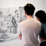 Unos turistas observan otra de las obras de la exposición