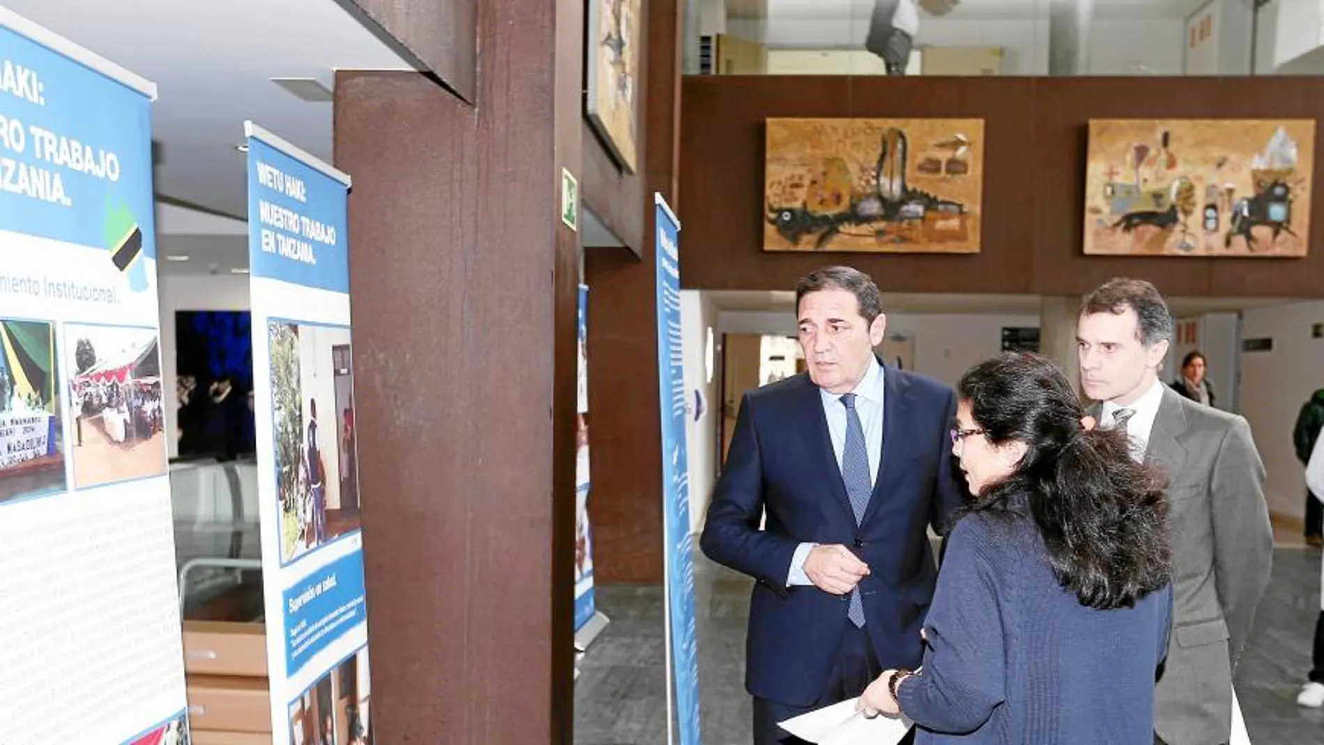El consejero de Sanidad, Antonio Sáez Aguado, el secretario de Presidencia, José Manuel Herrero, y la voluntaria de Médicos del Mundo, Gloria Chávez, visitan la muestra «Wetu Haki»