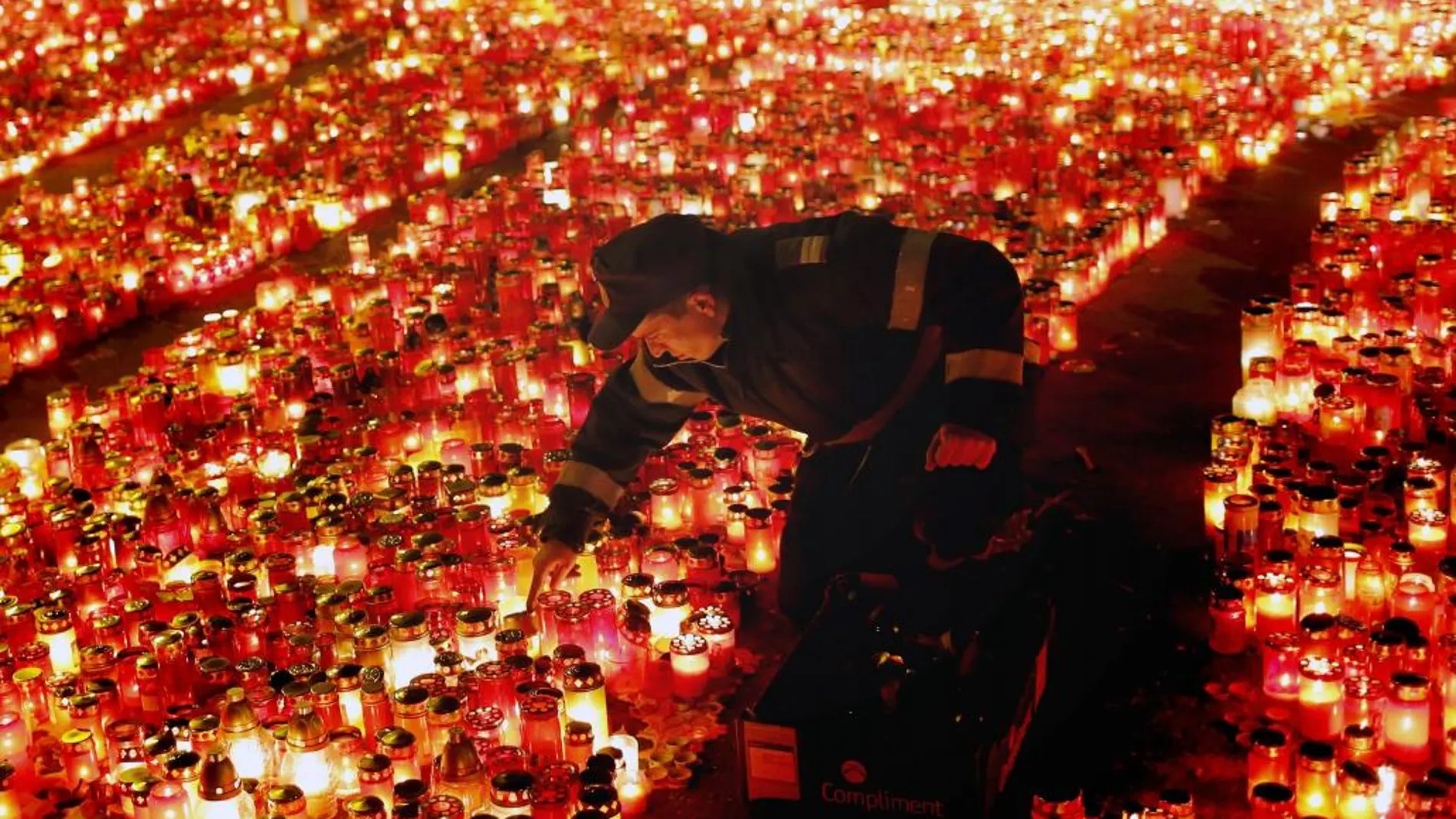 Un policía rumano ordena las velas encendidas en tributo de las víctimas de un incendio en una discoteca, el lunes 2 de noviembre de 2015, en Bucarest