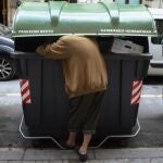 Una mujer rebusca en un contenedor de basura en una calle de Bilbao