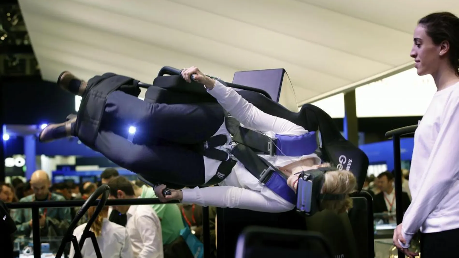 Una visitante prueba un simulador de vuelo acrobático de realidad virtual durante el Mobile World Congress (MWC)