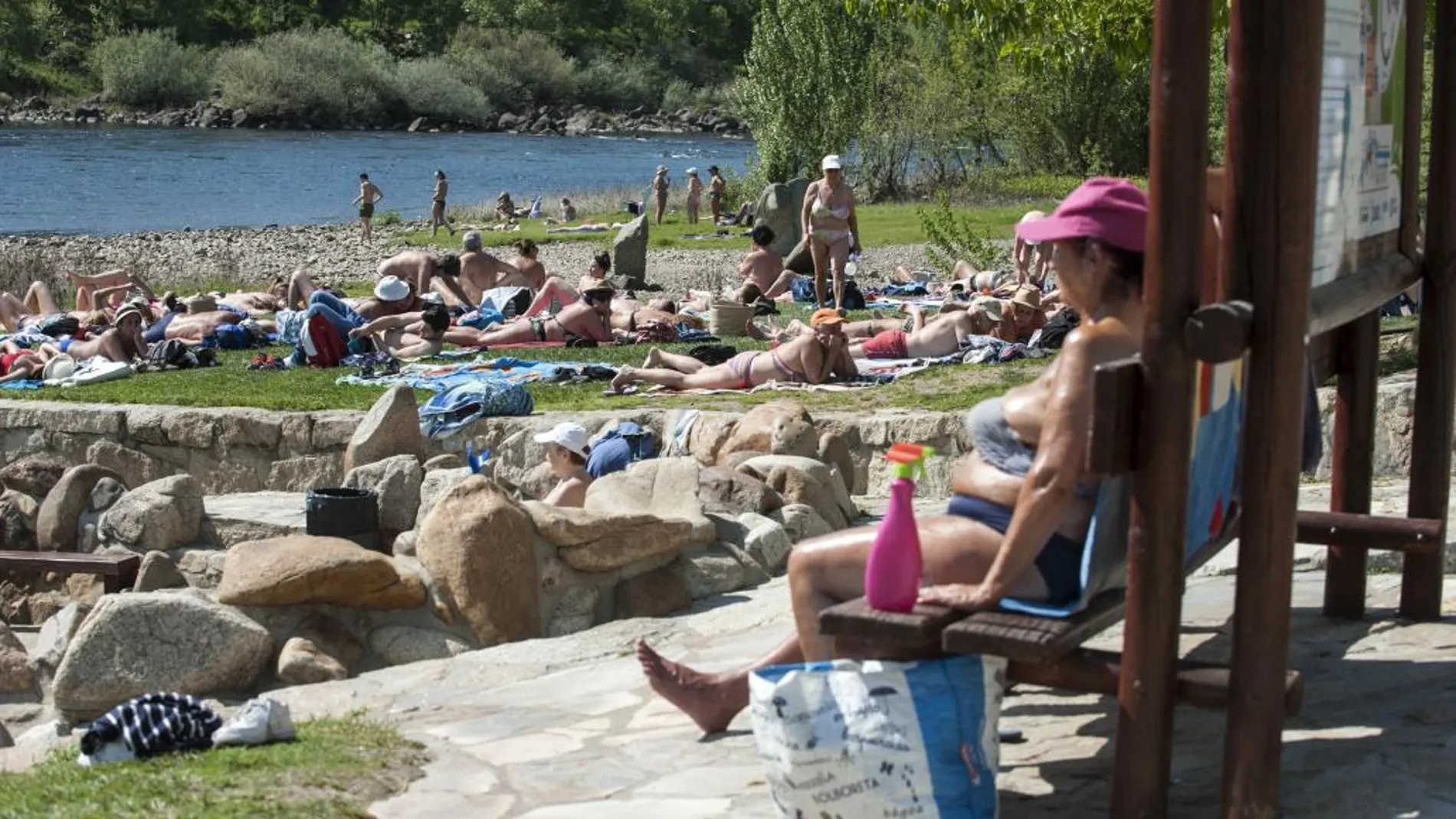 Varias personas disfrutan del buen tiempo en la zona fluvial del río Miño y las termas de A Chavasqueira