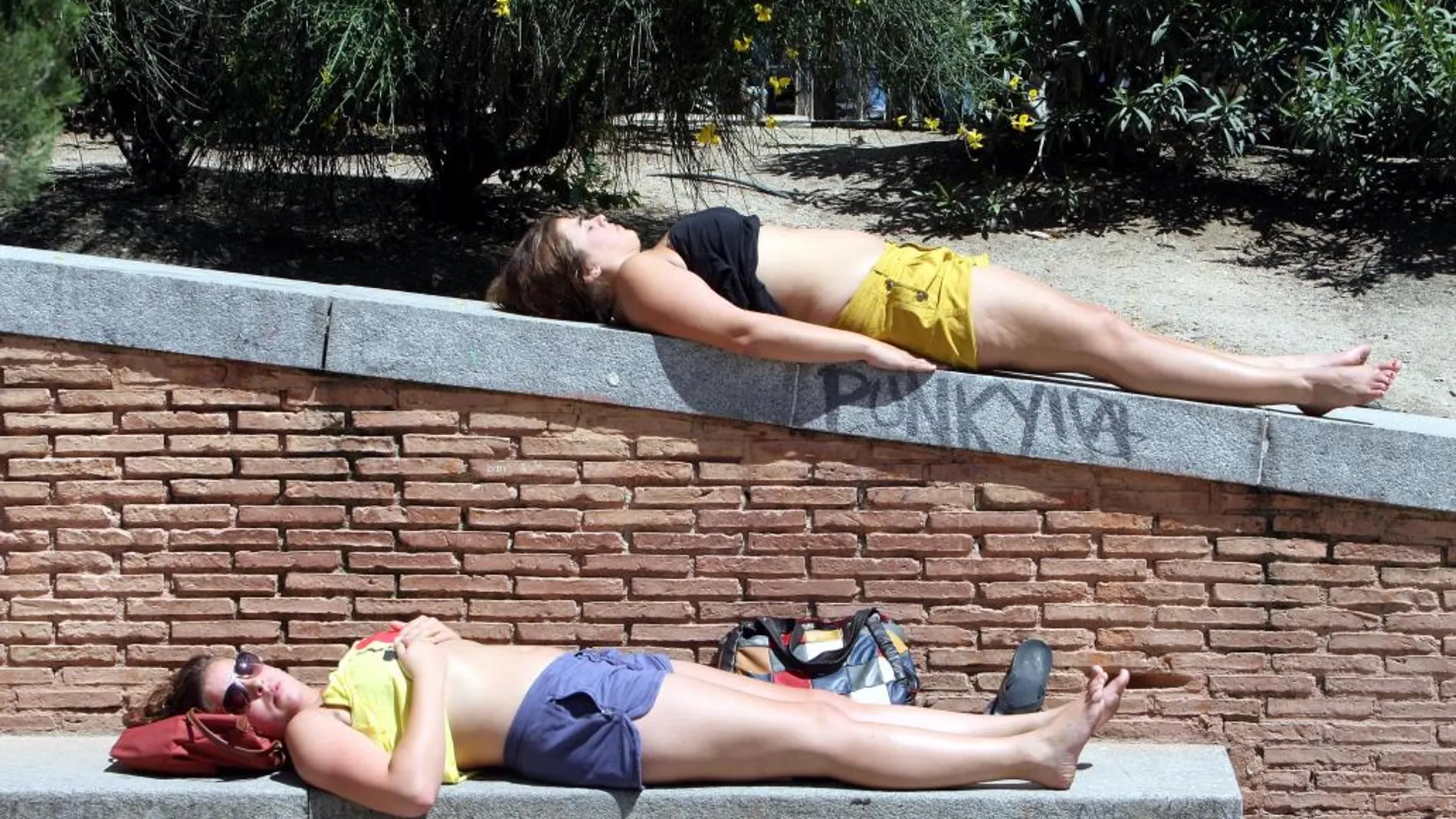 Dos jóvenes se echan la siesta en una plaza de Madrid