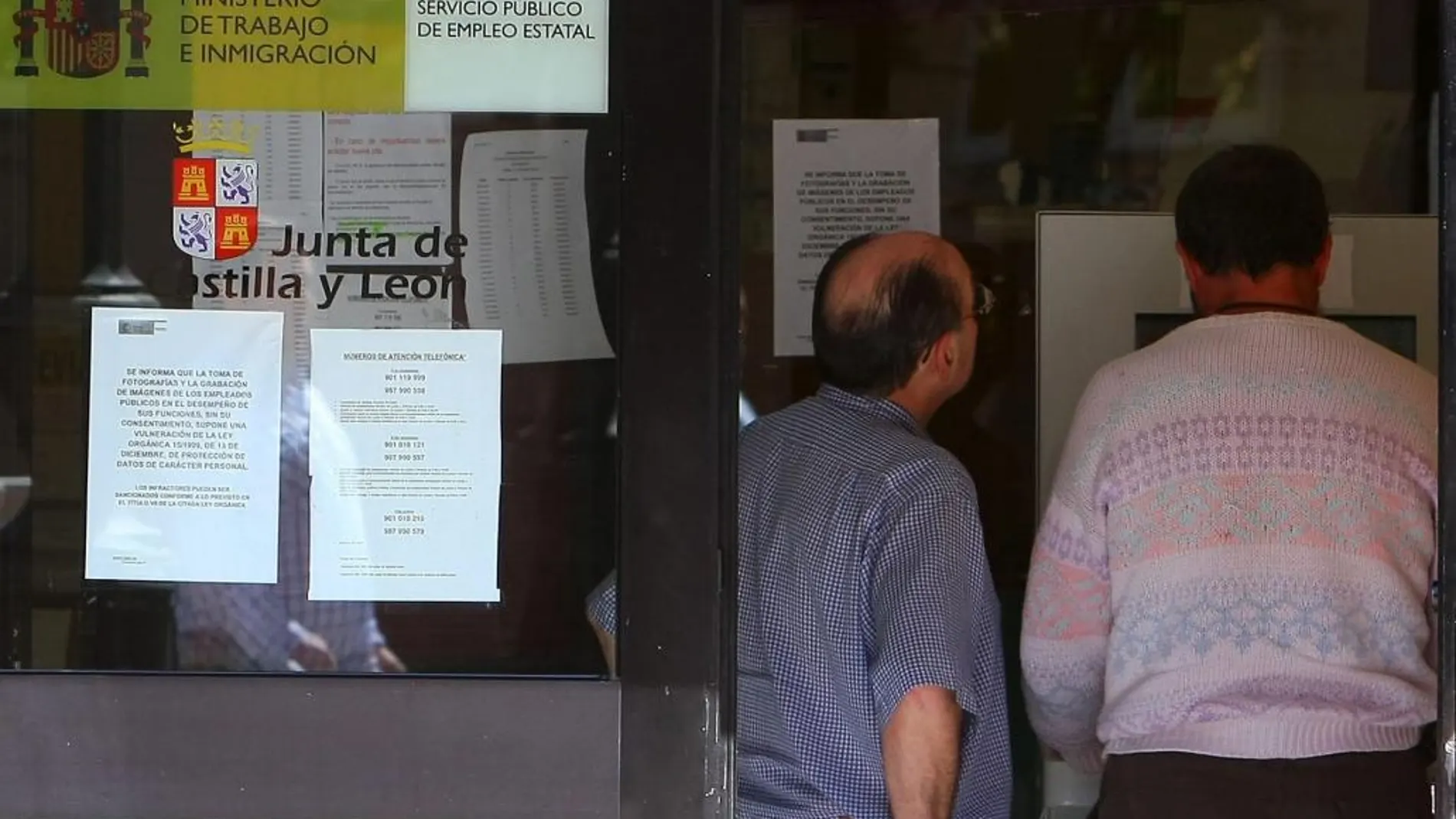 Dos hombres consultan los avisos de la oficina del Servicio Público de Empleo (ECYL) de Ponferrada (León)