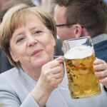 Angela Merkel sostiene una jarra de cerveza durante un acto electoral de la CDU en Múnich.