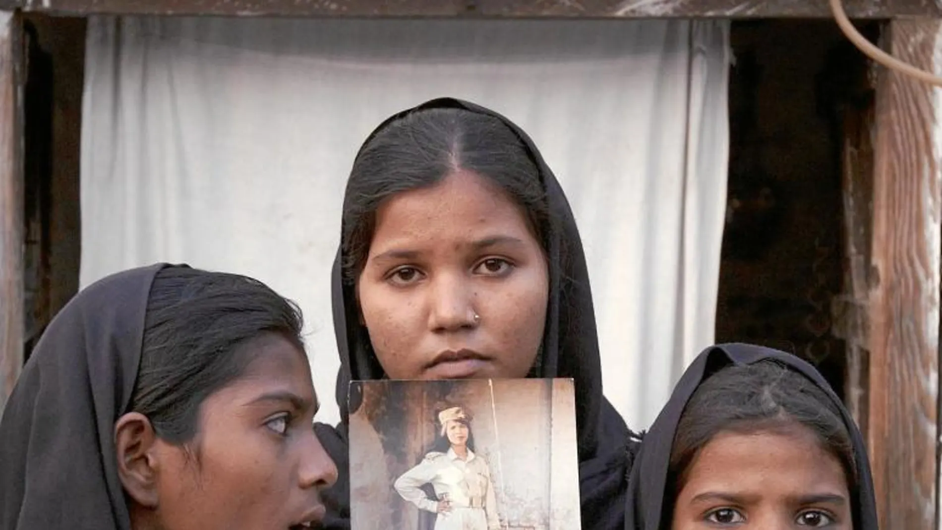 Las hijas de Asia Bibi posan con una foto de su madre en 2010, poco después de su detención