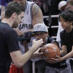 Pau Gasol (i), firma un balón para un niño durante un calentamiento previo a su partido contra Utah Jazz.