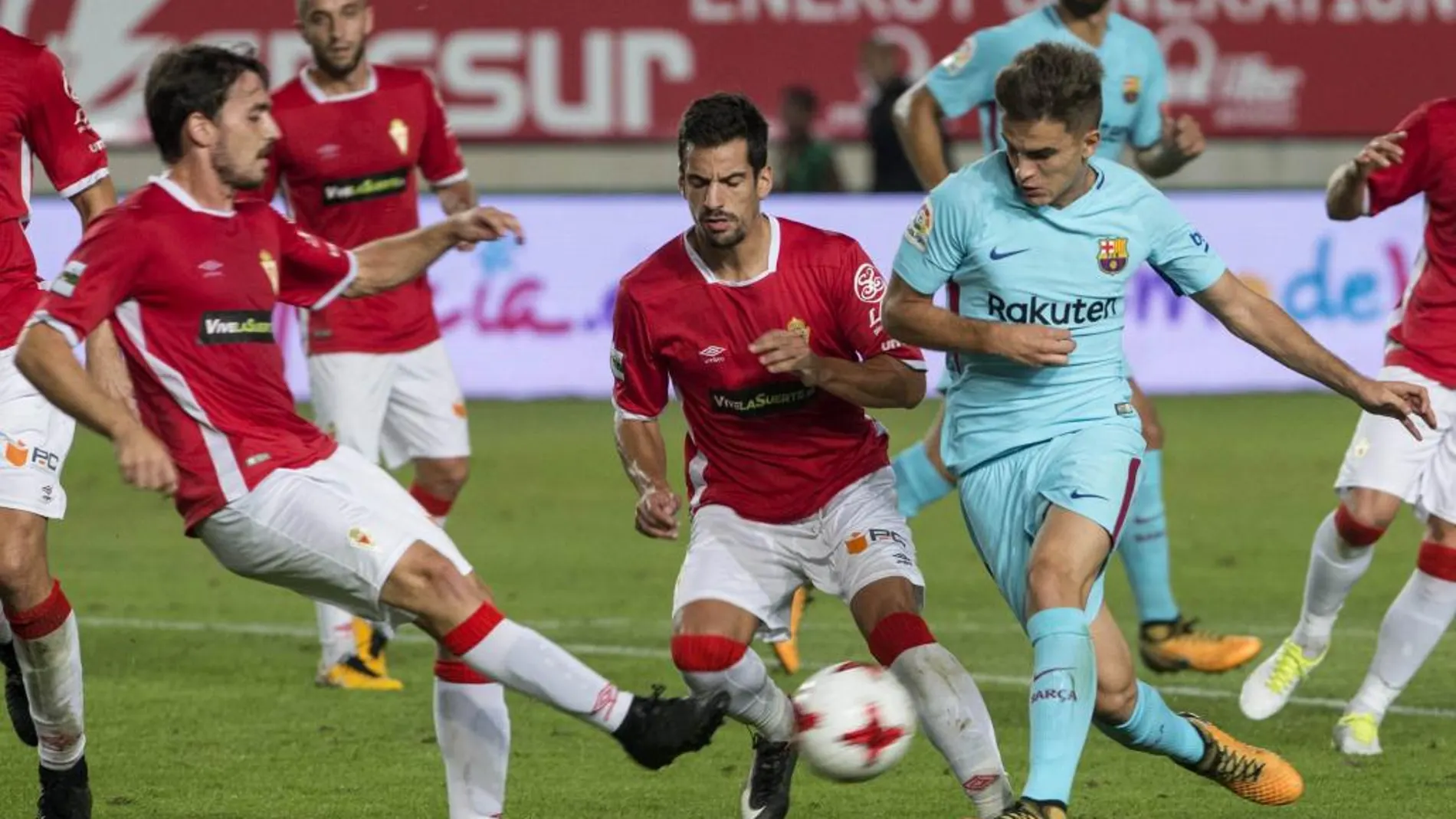 El centrocampista del F.C Barcelona Denis Suárez (d) intenta llevarse el balón ante los jugadores del Real Murcia, Antonio Escribano (i) y Pedro Orfila