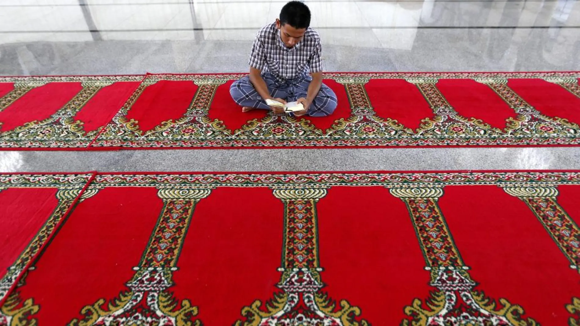 Un musulmán de la ciudad de Aceh lee el Corán mientras espera el final del ayuno en la mezquita de Darussalam, Aceh, Indonesia