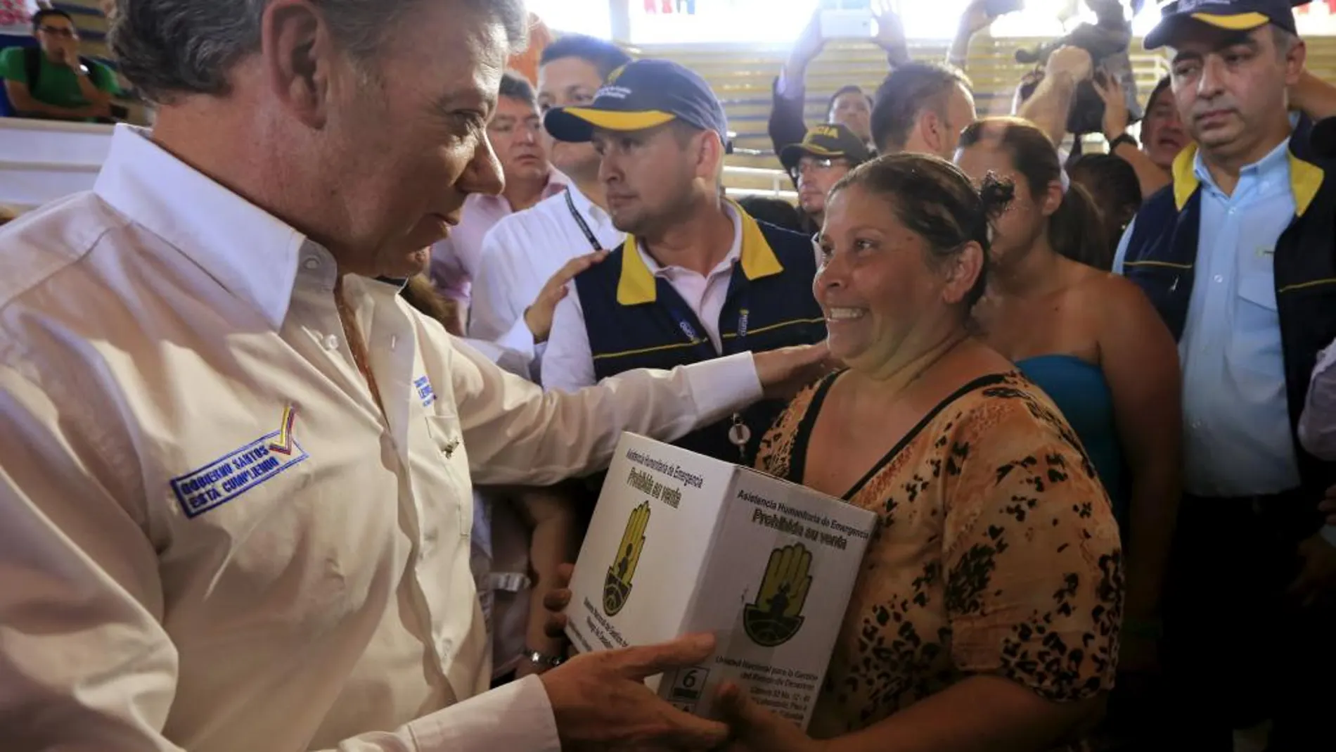 El presidente de Colombia, Juan Manuel Santos, entrega una caja de ayuda humanitaria a una mujer deportada por Venezuela