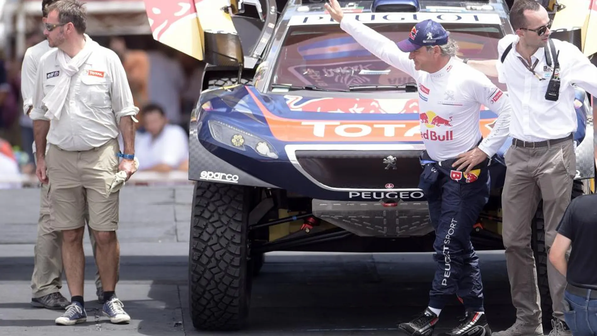 El piloto español Carlos Sainz (2-d) saluda al público en la larga simbólica del Rally Dakar 2016