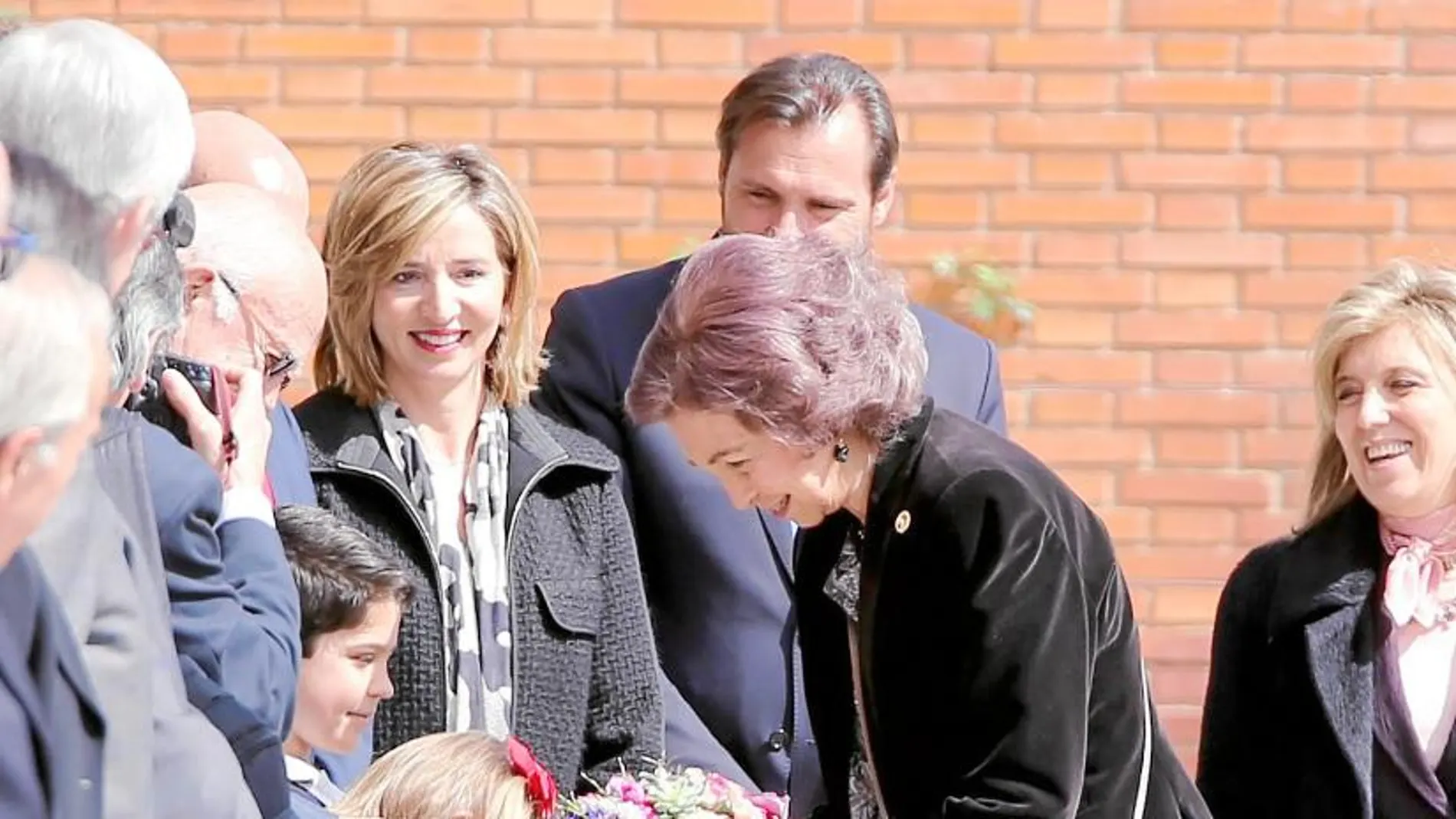 Un niña entrega a la Reina Sofía un ramo de flores a su llegada