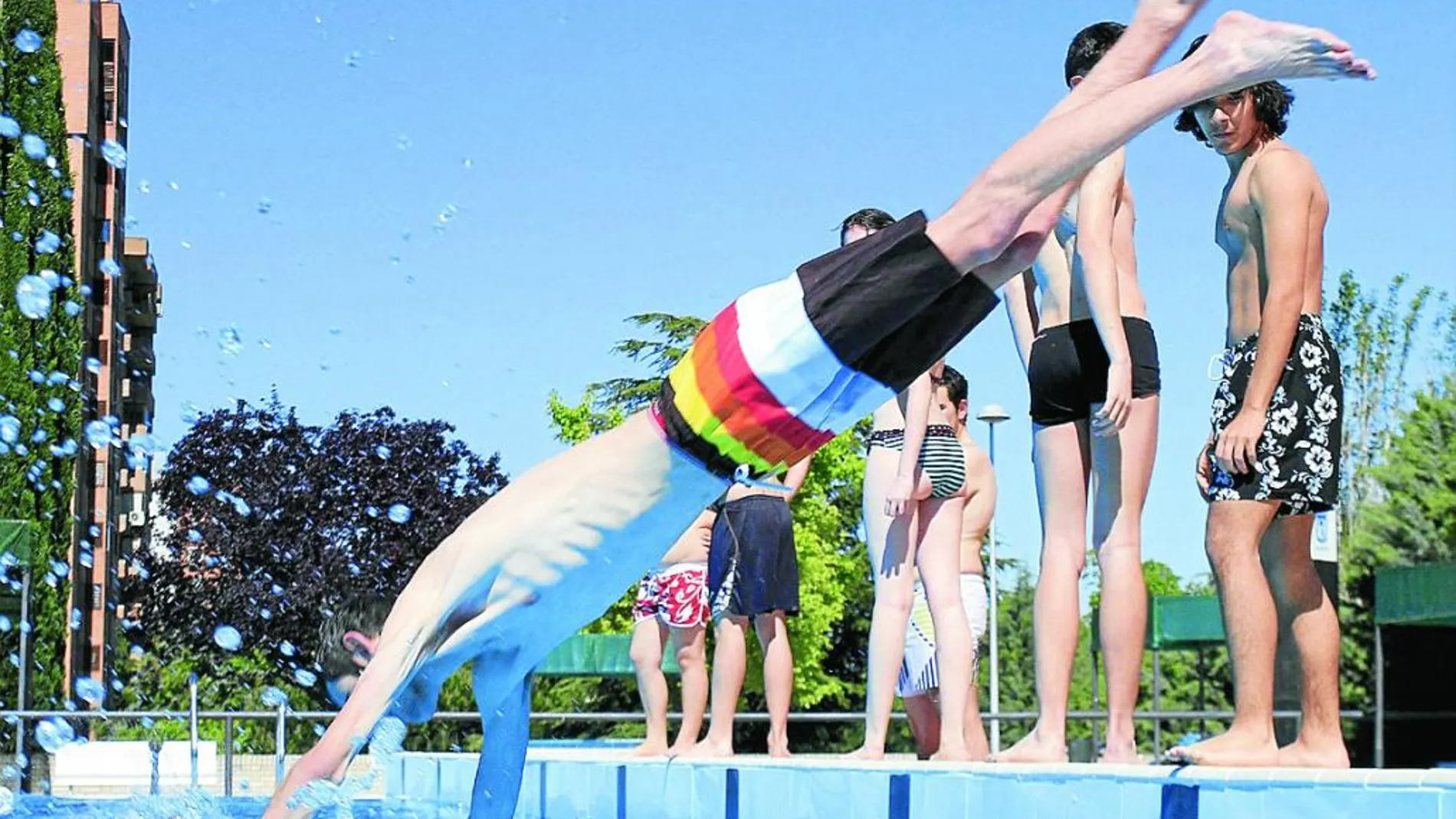 Un joven se lanza al agua en el primer día de apertura de las piscinas.