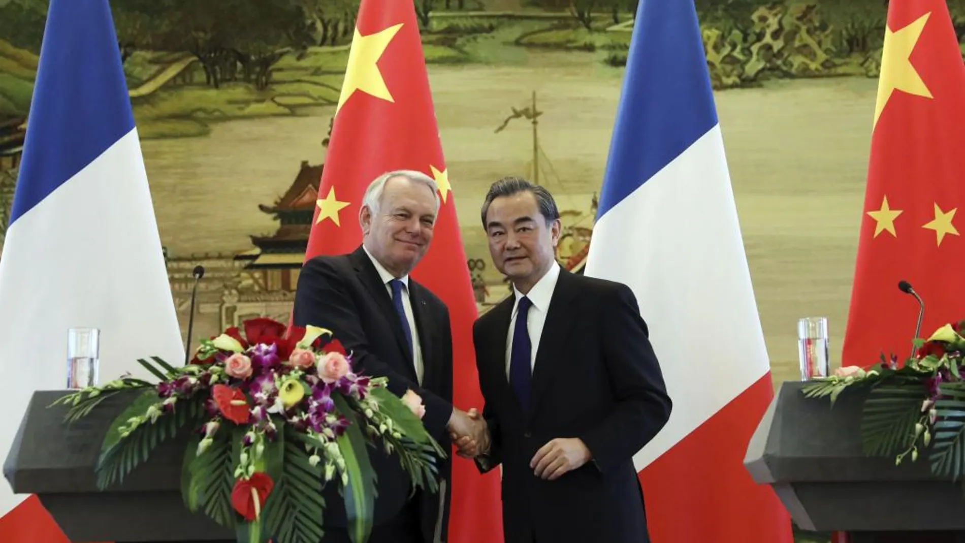 El ministro de Asuntos Exteriores chino, Wang Yi (d), estrecha la mano de su homólogo francés, Jean-Marc Ayrault, durante una rueda de prensa conjunta.