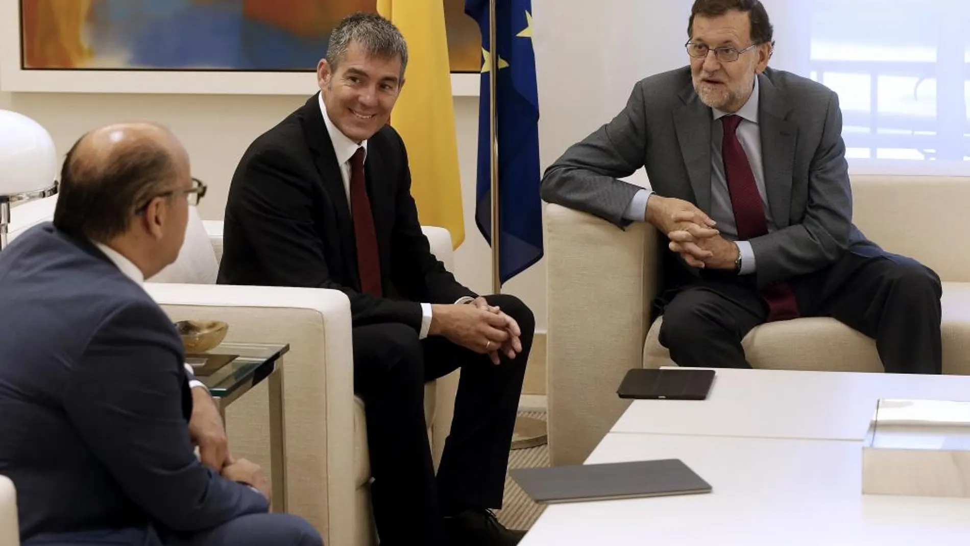 El presidente del Gobierno, Mariano Rajoy (d), conversa con el secretario general de Coalición Canaria, José Miguel Barragán (i), en presencia del presidente de Canarias, Fernando Clavijo (c)