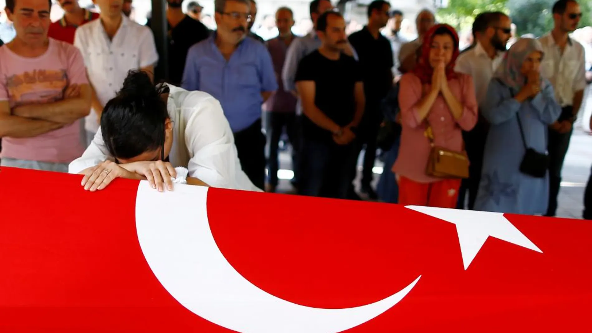 Un familiar de Gulsen Bahadir, una de las víctimas del atentado, llora sobre el féretro cubierto con la bandera turca