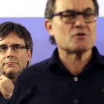 El presidente de la Generalitat, Carles Puigdemont (i), escucha al presidente de CDC, Artur Mas, tras el anuncio de los resultados del "supersábado", el 21 de mayo