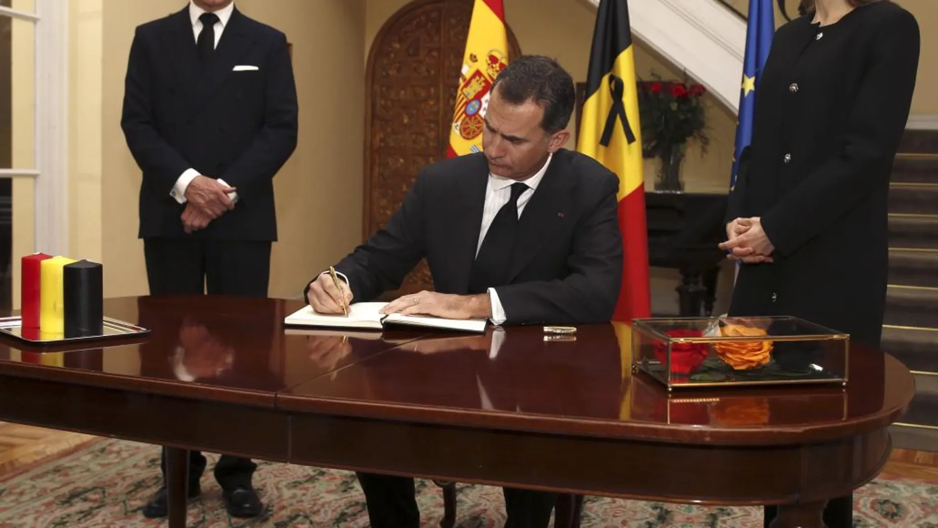 El rey Felipe, en presencia de la reina Letizia y del embajador de Bélgica en España, Pierre Labouverie (i), firma en el libro de condolencias en la residencia del embajador.