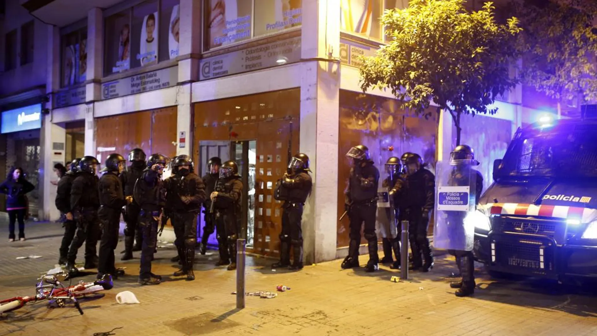 Varios antidisturbios junto al "banco okupado", esta noche en Barcelona, donde se ha vivido una nueva noche de disturbios en el barrio de Gràcia y donde se han reproducido los enfrentamientos entre jóvenes y fuerzas antidisturbios de los Mossos d'Esquadra.