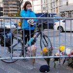 Una mujer baja de su bicicleta y llora frente a un memorial por las víctimas