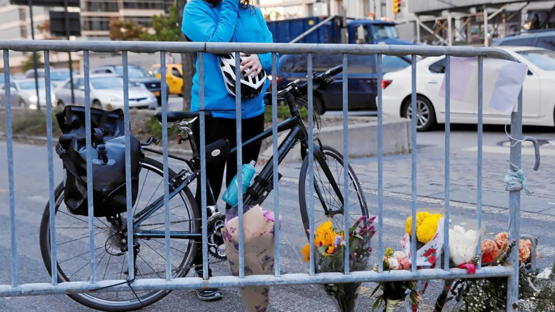 Una mujer baja de su bicicleta y llora frente a un memorial por las víctimas