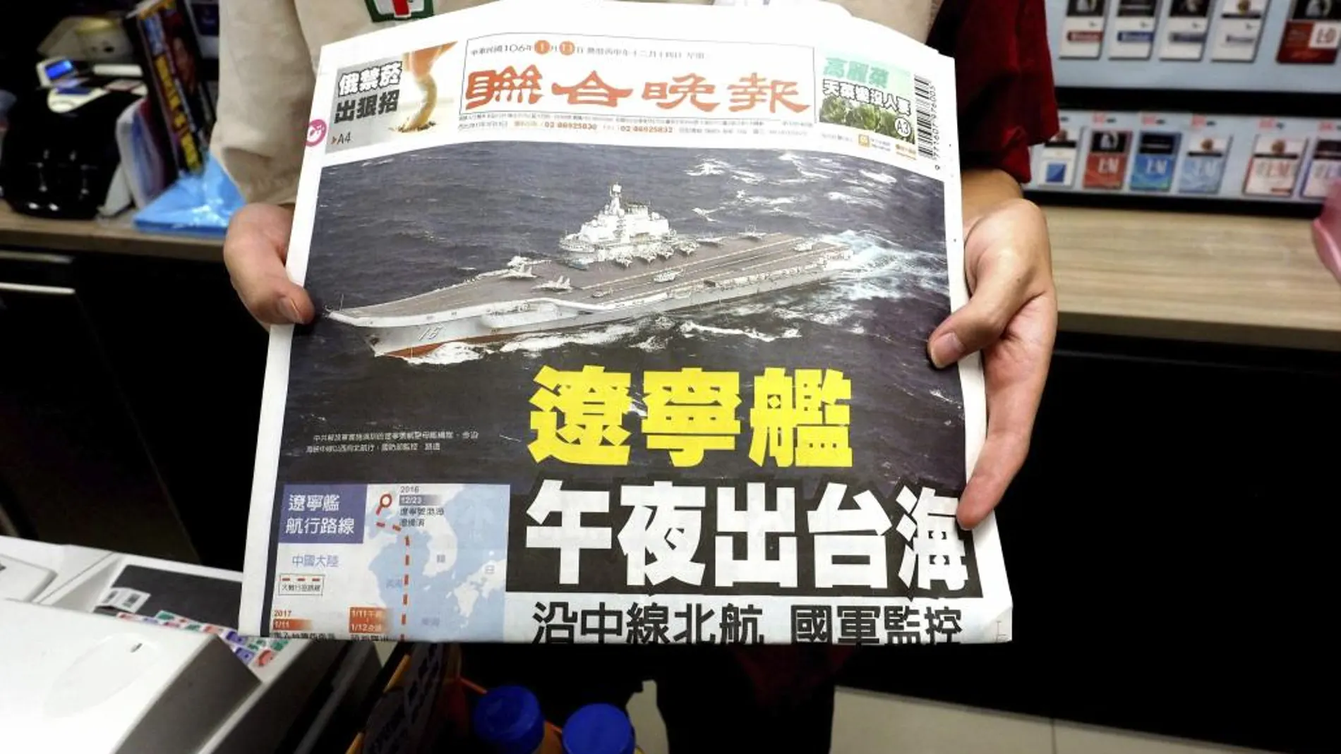Un dependiente taiwanés muestra la portada del periódico «United Evening News» con la imagen de un portaviones chino cruzando el estrecho de Taiwán