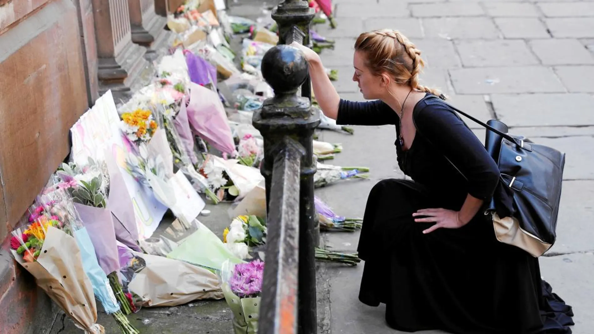 Una mujer deja un ramo de flores en el centro de Manchester para honrar a las víctimas del ataque en el Manchester Arena