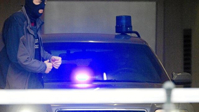 Un policía belga encapuchado prepara un vehículo para transportar a Salah Abdeslam