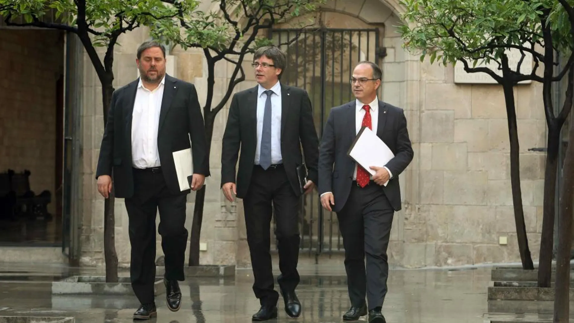 El presidente de la Generalitat, Carles Puigdemont, junto al vicepresidente, Oriol Junqueras, y el conseller de Presidencia, Jordi Turull (d), a su llegada a la reunión semanal del Govern