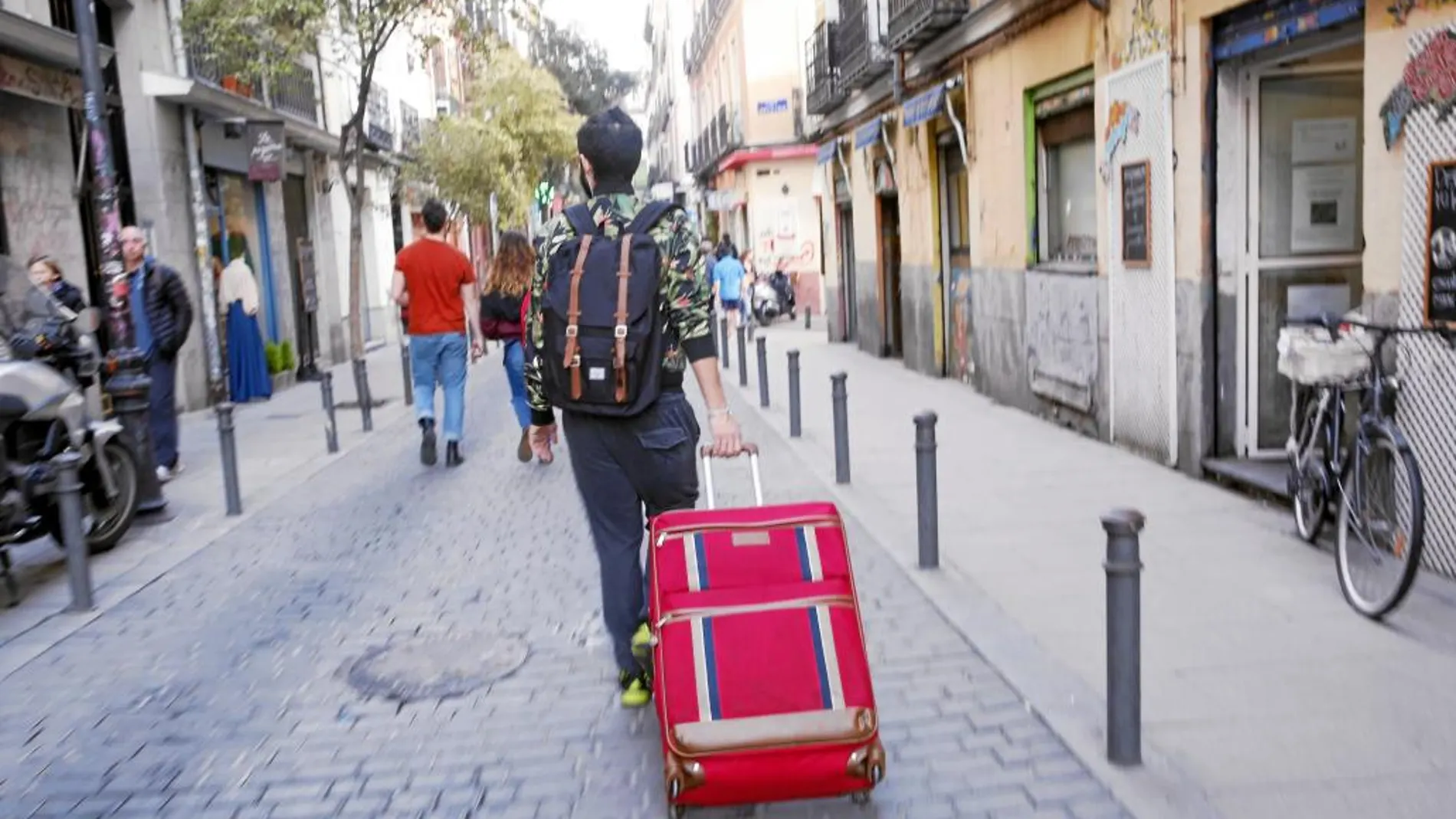 Un turista recorre las calles del barrio de Malasaña, uno de los más afectados por la «turistificación», con una maleta